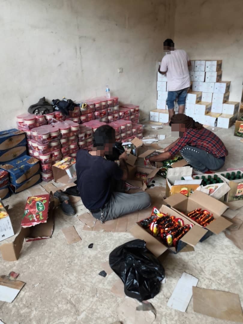 Three persons are packing groceries in a warehouse in Tal Tamr.
