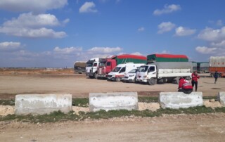 Trucks and vans standing on a dusty parking lot.