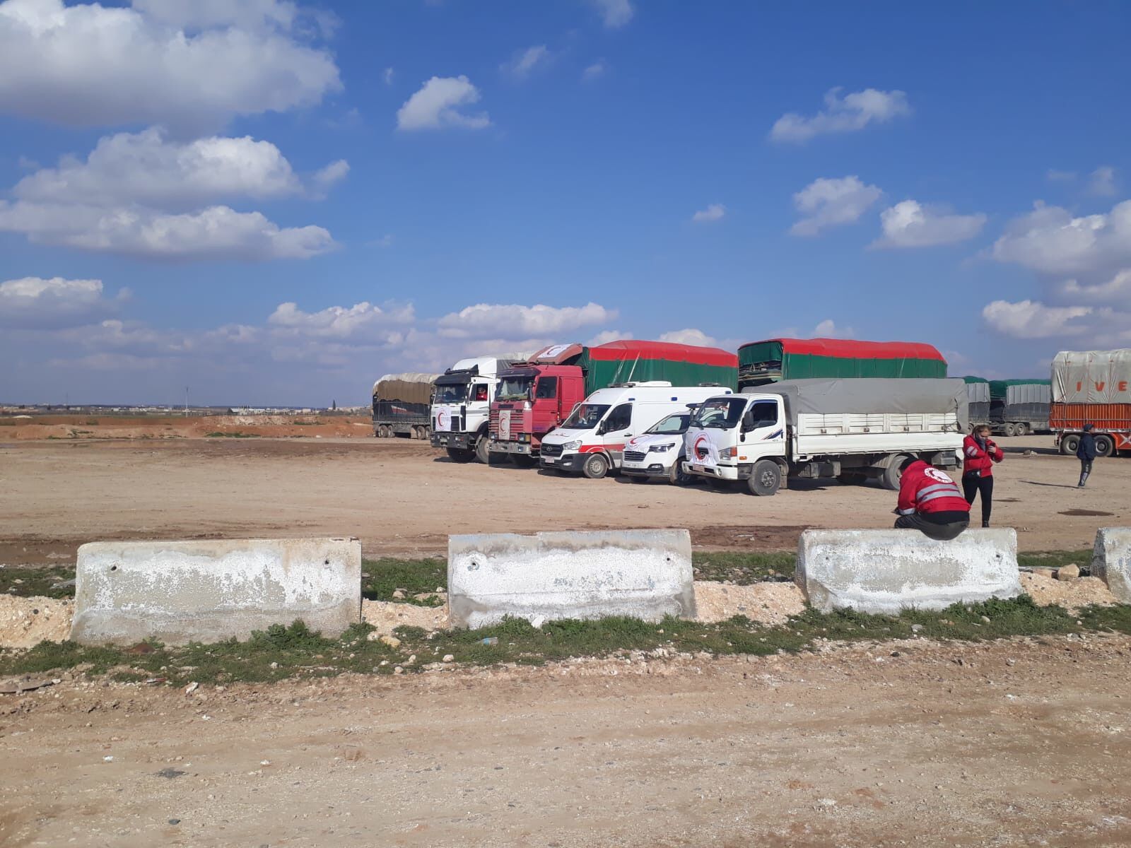 Trucks and vans standing on a dusty parking lot.