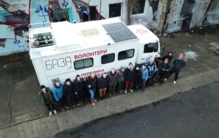 Eine Reihe von ca. 15 Personen vor einem weißen LKW aus der Vogelperspektive.