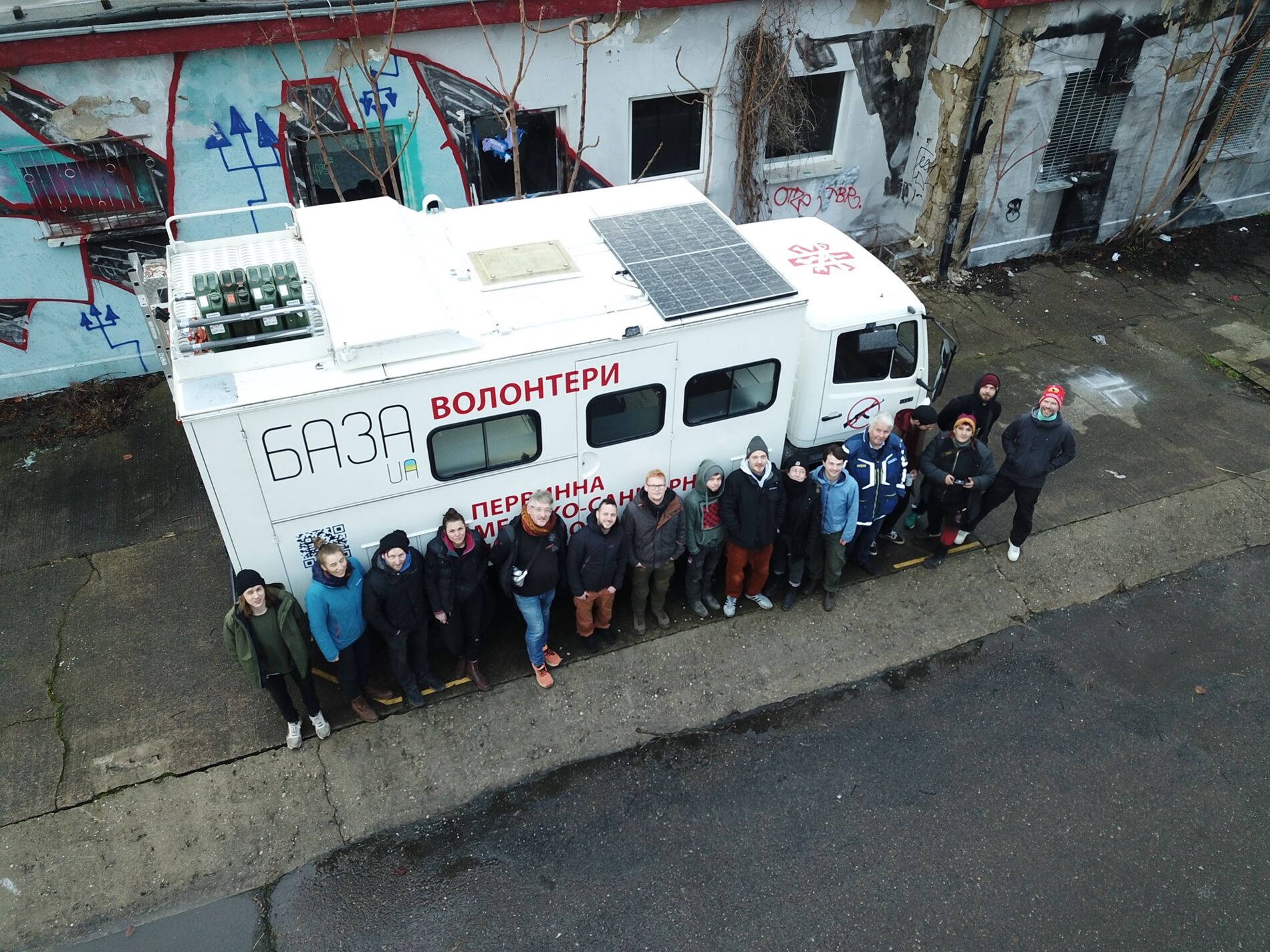 Eine Reihe von ca. 15 Personen vor einem weißen LKW aus der Vogelperspektive.