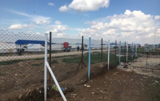 Ein Weg im eingezäunten Geflüchtetencamp al-Hol mit Zelten des UNHCR im Hintergrund. ©CADUS